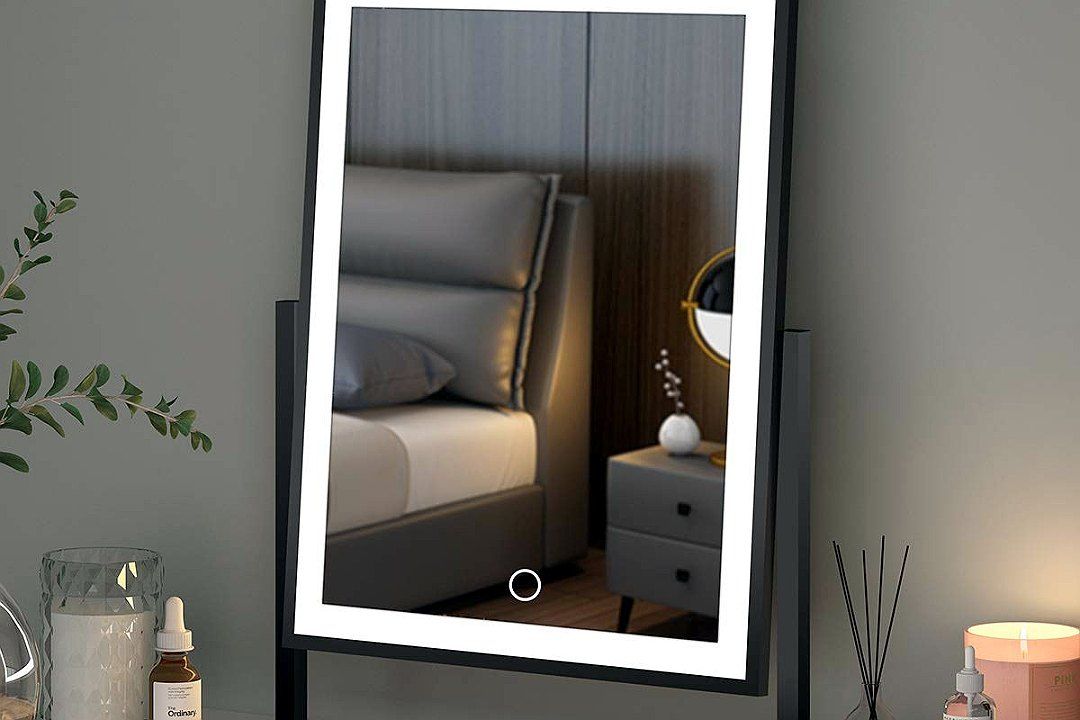 Black-framed rectangular LED vanity mirror lit on a bedroom dresser with candles