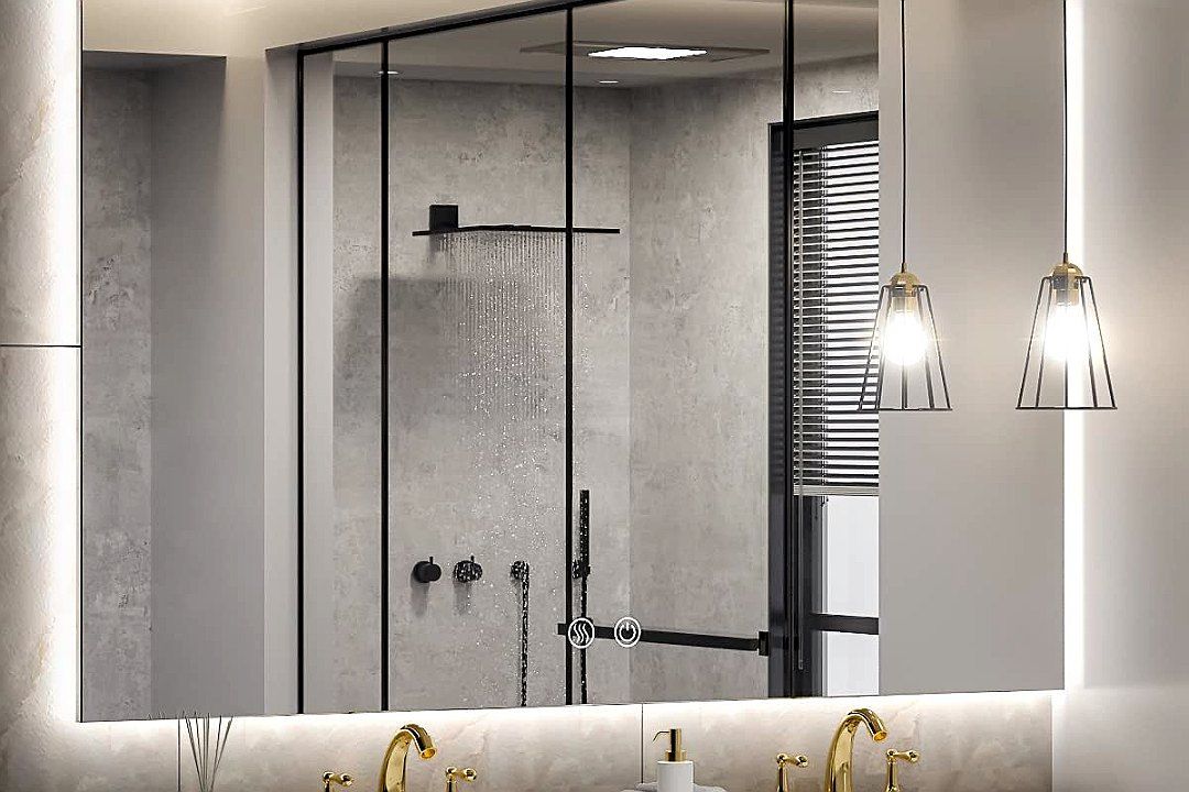Large rectangular backlit mirror over a double vanity with gold faucets