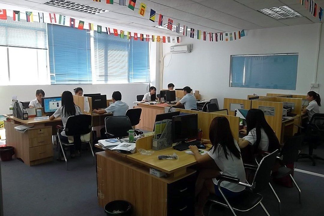 业务员在工位电脑前工作,天花板挂满各国国旗
