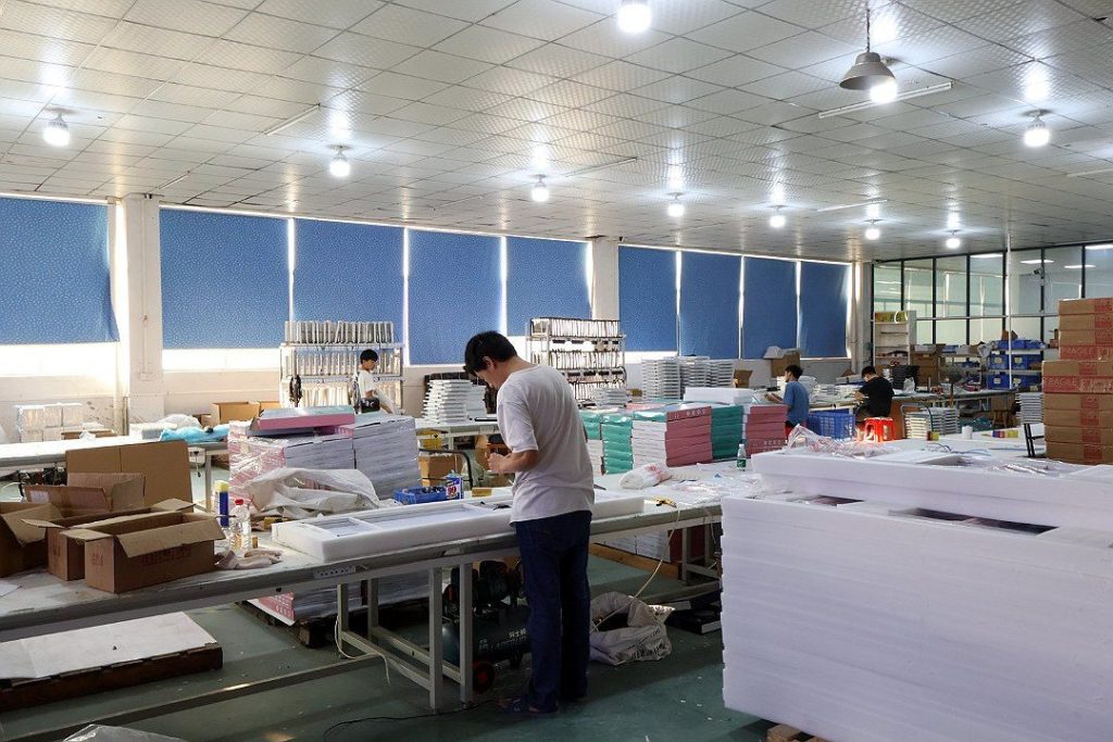 工人在工作台上包装产品，周围堆放纸箱、白色泡沫护角和成品
