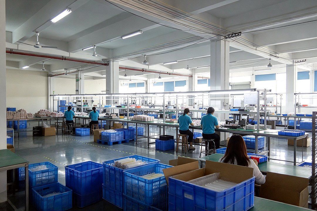 Material racks, turnover boxes and workbenches, with workers operating at their stations in the background