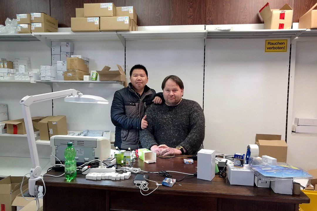 Group photo at a desk in a customer's warehouse, with LED lighting packaging boxes on the shelves