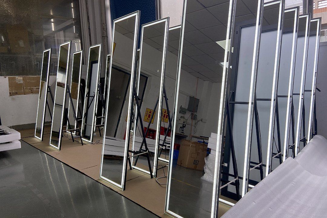 Rows of upright, powered-on LED full-length mirrors in the workshop, with the light strips on dozens of mirror frames lit at the same time…