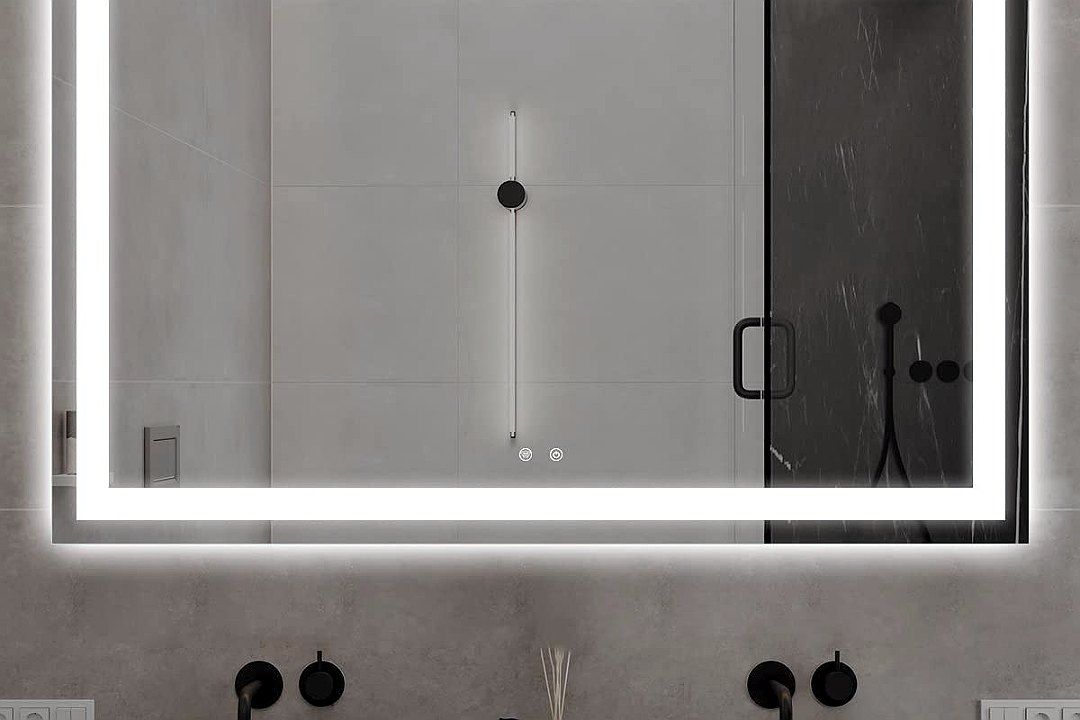 A frameless backlit rectangular LED mirror mounted above a double vanity, lit with white light around its edges, in a marble bathroom