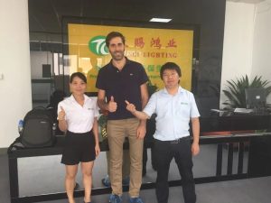 An overseas customer visiting the factory, posing with our sales staff at the Tianci Hongye / TIANCI LIGHTING reception wall.