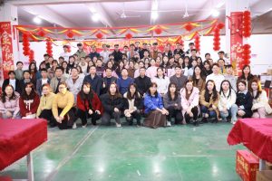 All-staff photo at the Tianci Hongye 2025 Spring Festival gala inside the factory.
