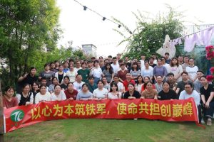 Company team-building: nearly a hundred employees outdoors with a Tianci Hongye banner.